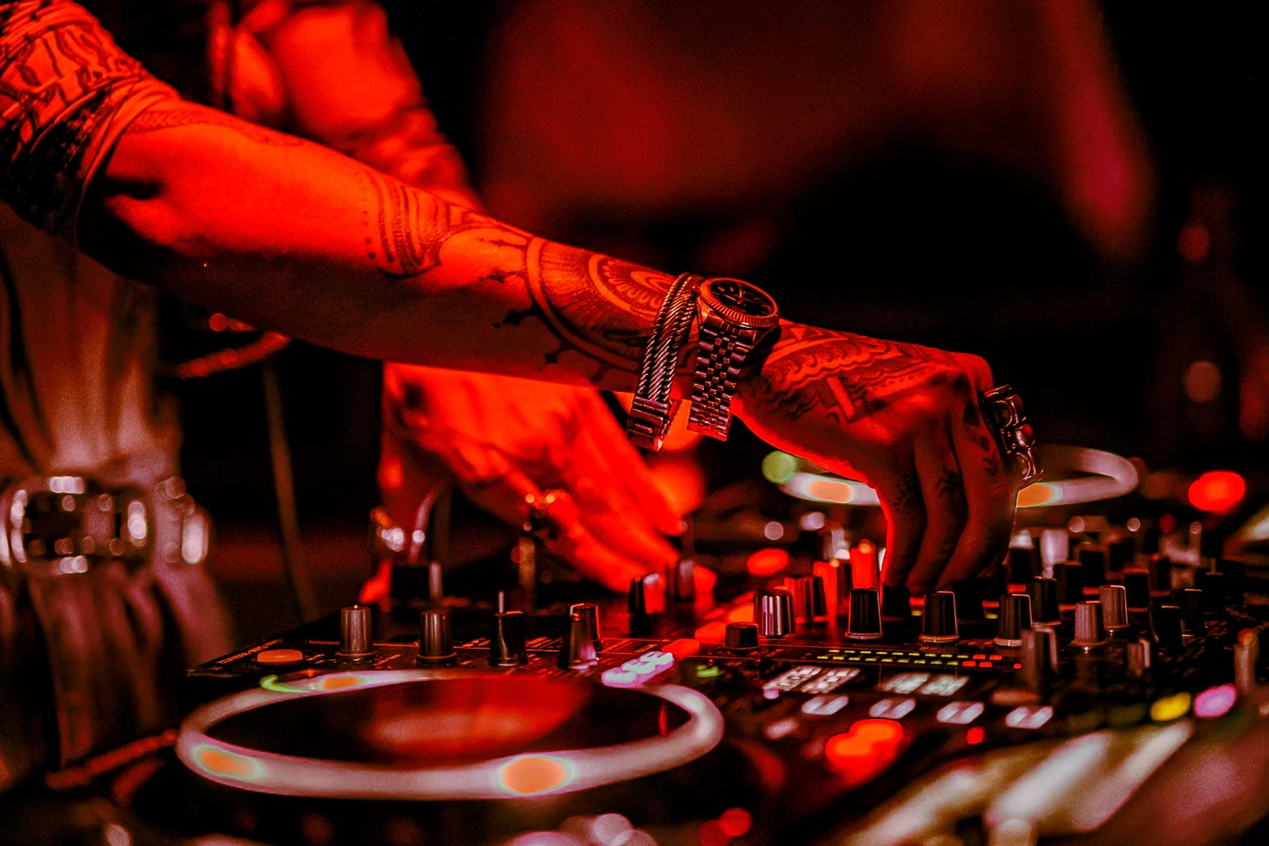 Las manos de un DJ sobre los platos y la mesa de mezclas